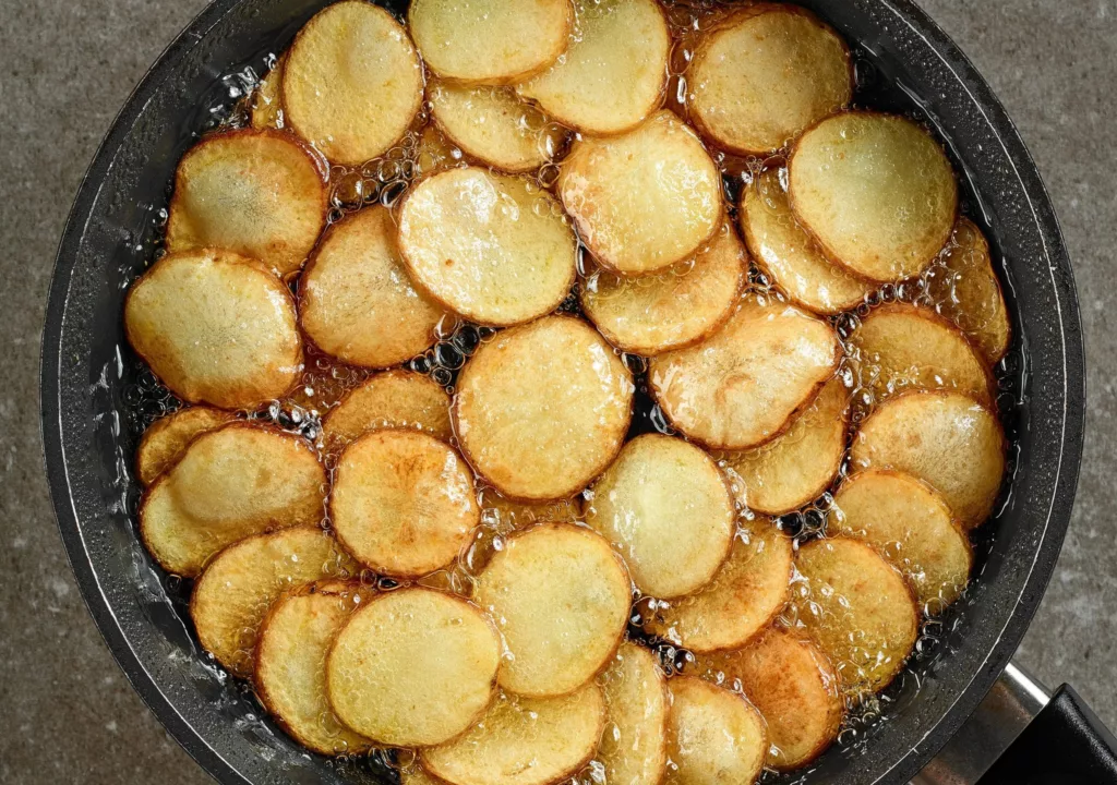 frying potatoes in pan with oil.