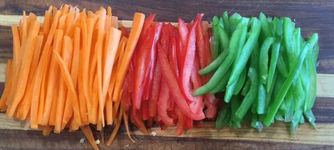 Finely julienned carrot, red bell pepper, and green bell pepper for quick cooking in a stir-fry.