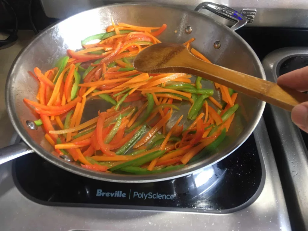 Stir frying carrots, green bell pepper, and red bell pepper for Calgary Ginger Beef recipe.