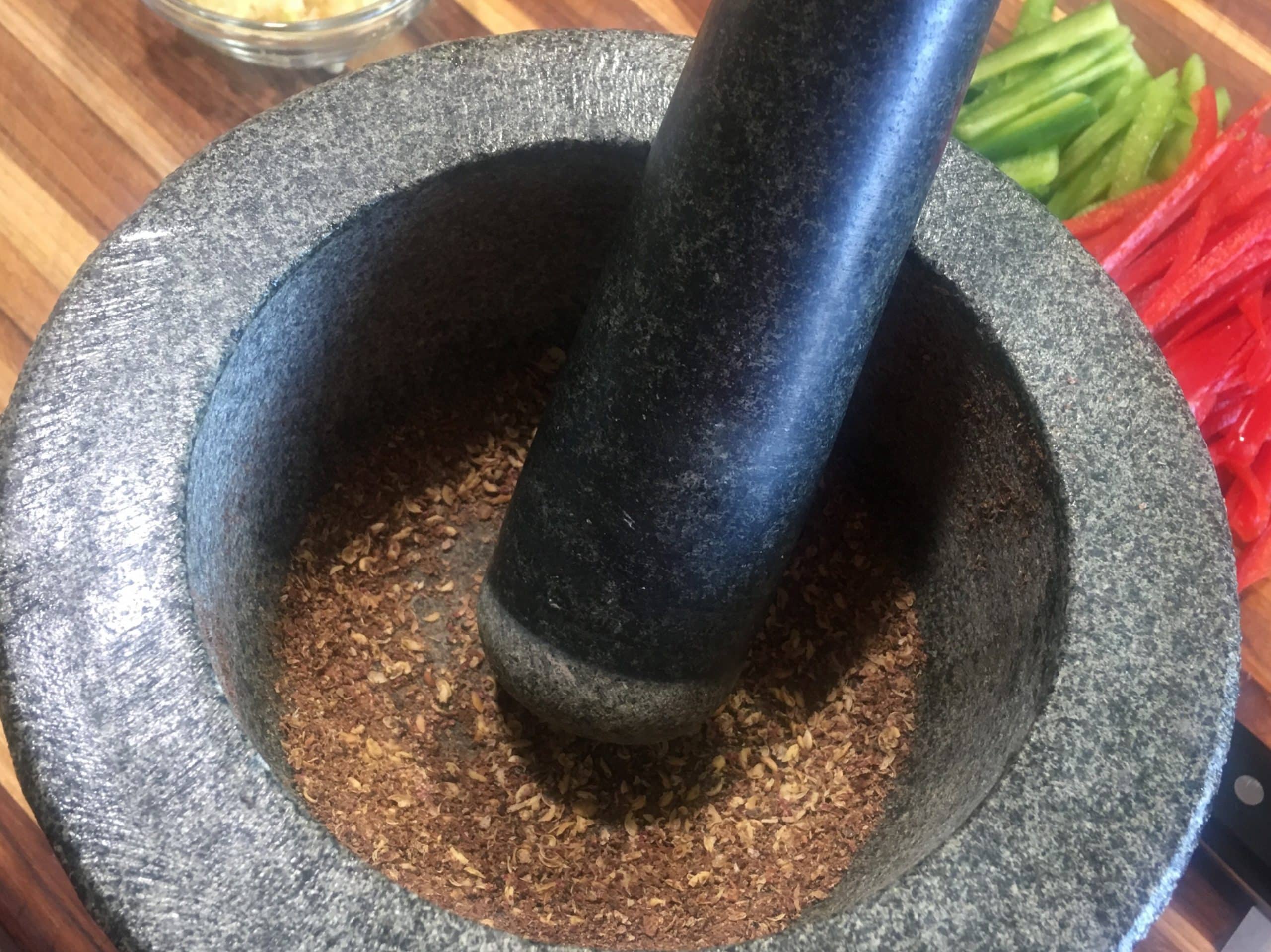 Grinding Szechuan peppercorns with a mortar and pestle for Calgary Ginger Beef.
