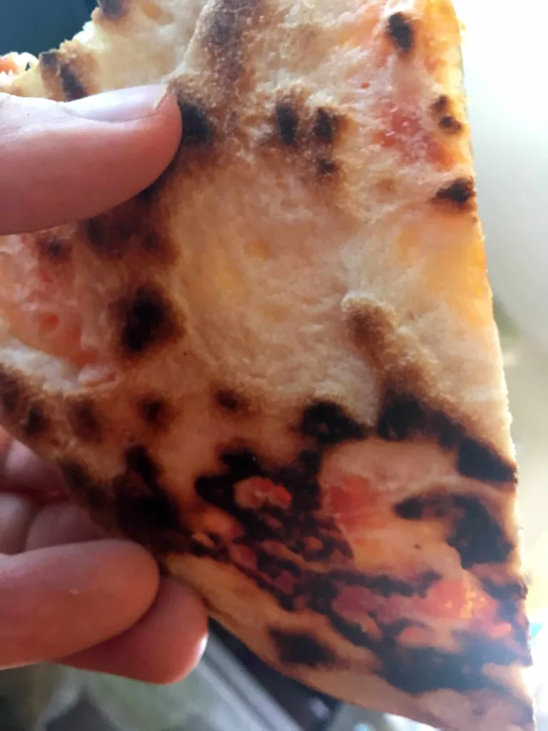 Charred blistering underside of a Neapolitan pizza cooked on a baking steel.