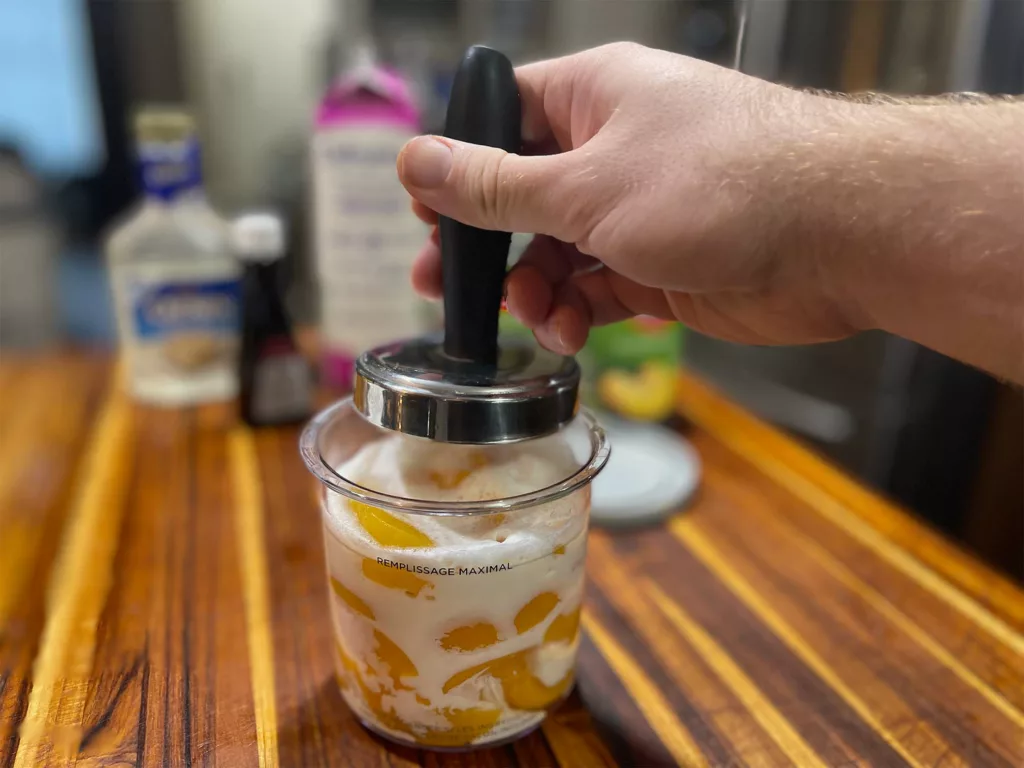 https://www.sizzleandsear.com/wp-content/uploads/2021/12/ninja-creami-review-tamping-the-peach-ice-cream-before-freezer-1024x768.webp